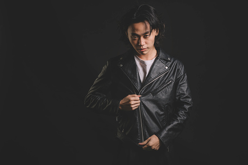 one asian chinese male model studio portrait with leather jacket cool attitude and black background