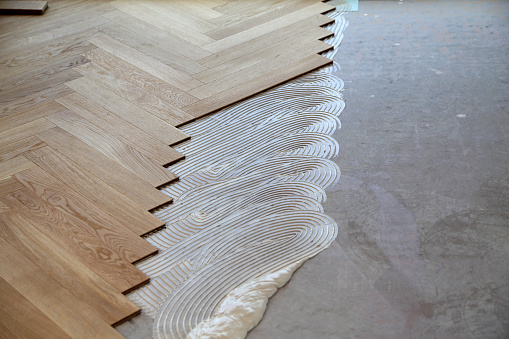 Worker laying parquet flooring. Worker installing wooden laminate flooring.