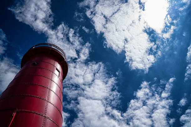 Iconic old red lighthouse on Lake Michigan with blue skies and puffy clouds