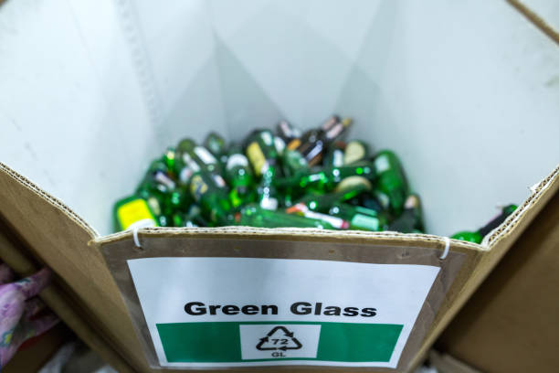 A person holding a plastic container filled with empty glass jars and bottles, preparing for waste sorting and recycling as part of a sustainable lifestyle and environmental conservation effort.