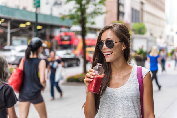City lifestyle woman drinking healthy fruit juice Urban city lifestyle hipster asian woman drinking healthy fruit vegetable berry juice smoothie walking on downtown street of New York city, NYC, USA. Happy young adult health diet concept. beet stock pictures, royalty-free photos & images