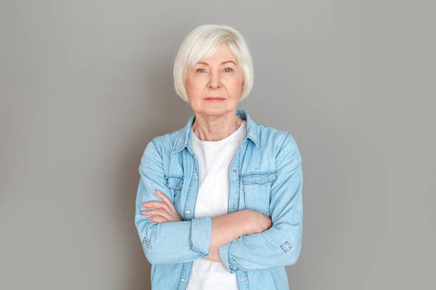 istock Senior woman in jeans jacket studio isolated on grey wall serious 1167664078