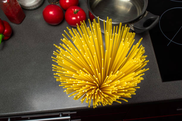 Cooking Italian spaghetti. Pasta, fresh vegetables, cheese parmesan, spices and kitchen utensils on the table, oven, pan. Top view