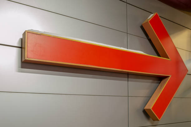 istock Large arrow-shaped pointer. Orange. Hanging on a gray steel wall. 1167664834