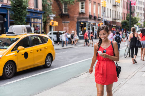 woman walking in new york city using phone app - chamada de fotografia imagens e fotografias de stock