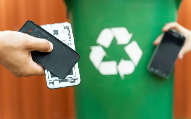 E waste , recycle concept , disassembled smartphone and recycle bin in background