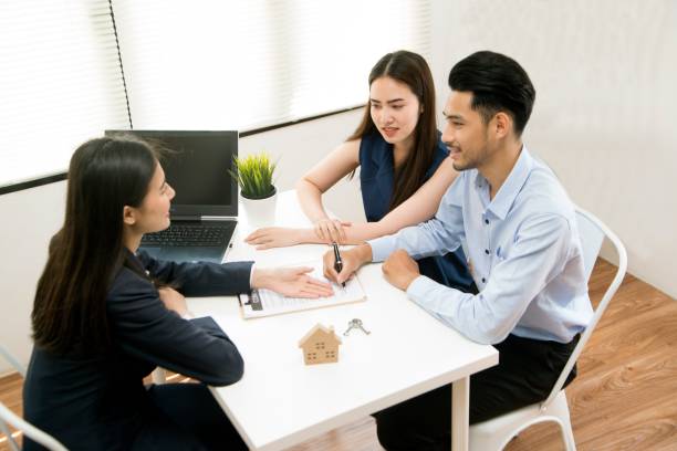 Asian female salesman sit in a modern office room and talk to customers and be satisfied with successful. Businesswoman shaking hand with a young couple in office. Bank agent and his client shaking hands in conference room. Happy smiling couple seal a deal with their personal financial adviser. angry general manager stock pictures, royalty-free photos & images