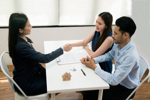 Asian female salesman sit in a modern office room and talk to customers and be satisfied with successful. Businesswoman shaking hand with a young couple in office. Bank agent and his client shaking hands in conference room. Happy smiling couple seal a deal with their personal financial adviser. angry general manager stock pictures, royalty-free photos & images