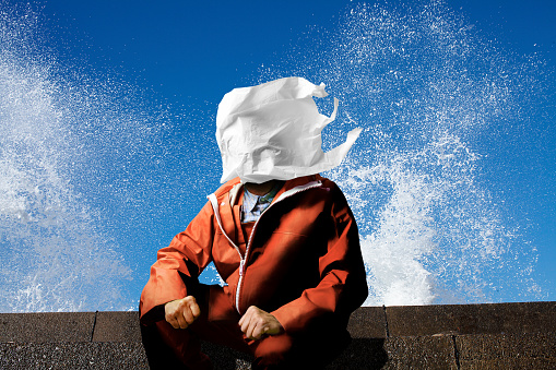 A plastic bag blown by the wind covers the fisherman's face. The background is a splash of waves struck by the quay and a clear blue sky.
Plastics become micro plastic particles by waves and ultraviolet rays and are present in seas around the world.

Aggravated plastic waste and dumping and micro plastic marine pollution.