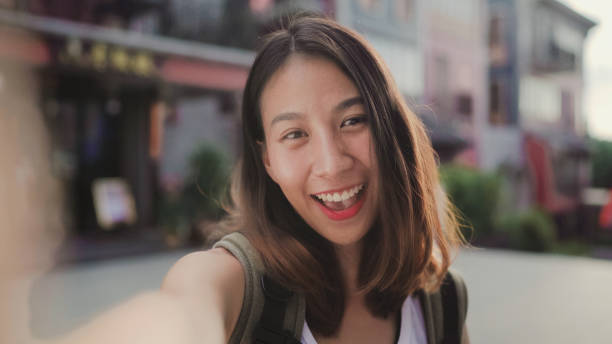 istock Cheerful beautiful young Asian backpacker blogger woman using smartphone taking selfie while traveling at Chinatown in Beijing, China. Lifestyle backpack tourist travel holiday concept. Point of view. 1167678490