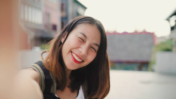 istock Cheerful beautiful young Asian backpacker blogger woman using smartphone taking selfie while traveling at Chinatown in Beijing, China. Lifestyle backpack tourist travel holiday concept. Point of view. 1167678492