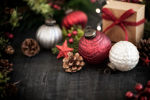 Christmas holiday vintage-rustic baubles and ornaments on a textured black wood background with defocused lights and copy space