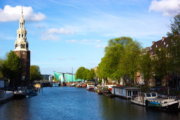 Amsterdam, Holland: The 17th-century Montalban Tower, canal and boats at dusk in central Amsterdam. The NEMO Science Museum (by architect Renzo Piano) is in the background.