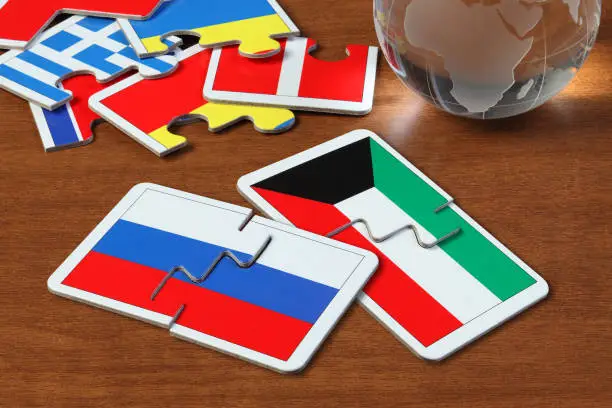 puzzle with the national flag of Russian and Kuwait on wooden table