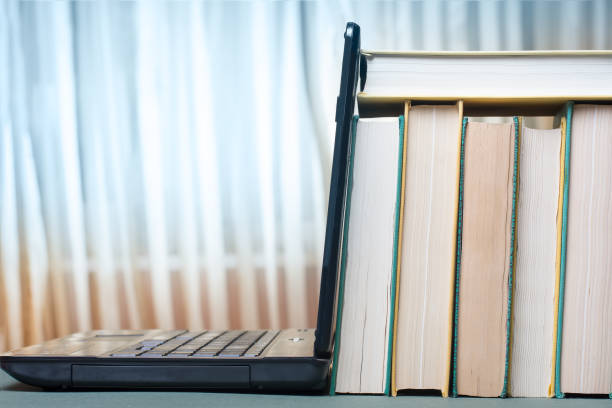 istock A stack of books and textbooks are leaning on a laptop. Educational concept. 1167686343