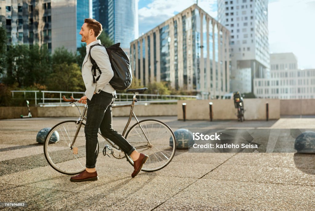 Time to kick this workday into high gear Shot of a young businessman traveling through the city with his bicycle Cycling Stock Photo