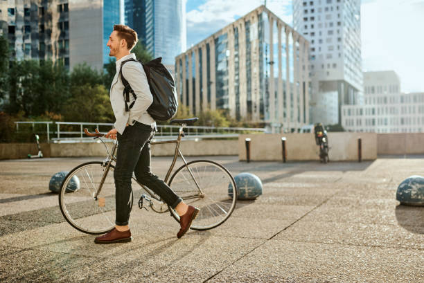 Time to kick this workday into high gear Shot of a young businessman traveling through the city with his bicycle businessman happiness outdoors cheerful stock pictures, royalty-free photos & images