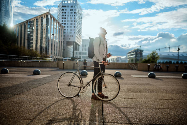 You determine your place in this world Shot of a young businessman using a smartphone while traveling through the city with his bicycle carbon footprint stock pictures, royalty-free photos & images