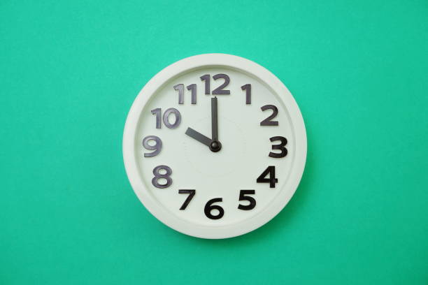 istock White round clock showing Ten o'clock on green background 1167697674