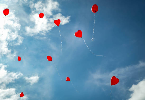 rote herz geformte ballons mit himmel hintergrund - heart balloon stock-fotos und bilder