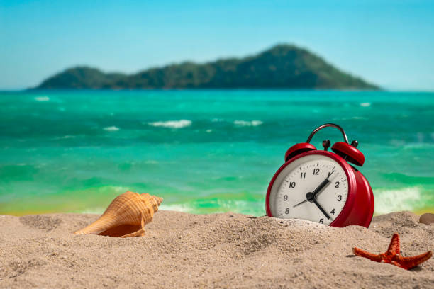 istock desk clock on the beach at sunset. 1167701625