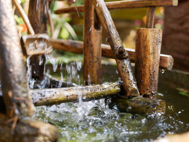 istock Selective focus of water drops falling from a bamboo hydraulic turbine onto a water surface and splashing in different directions 1167701649