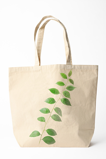 Canvas tote bag with leaves printed, isolated on white with clipping path. 
Concept of environmental and recycling.