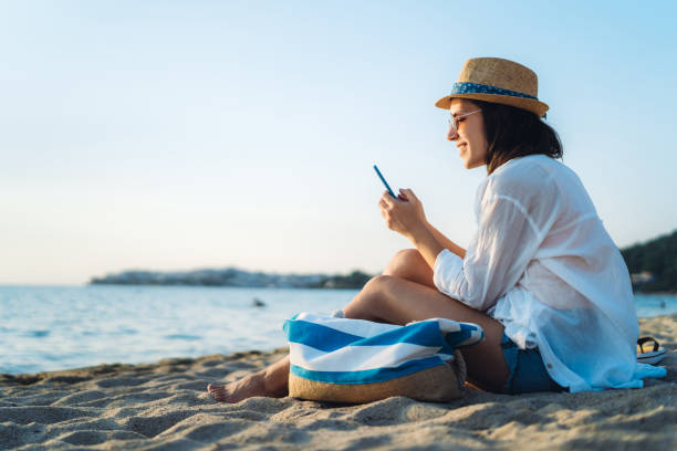 uso del telefono in spiaggia - vacations tourism travel white sand foto e immagini stock