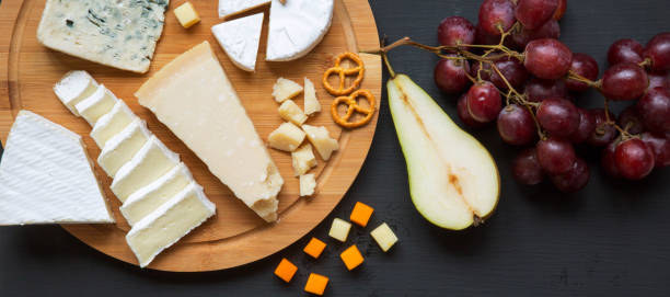 istock Tasting cheese with fruits, pretzels walnuts and bread sticks on a dark surface, overhead view. Food for wine. Top view. Close-up. 1167706199