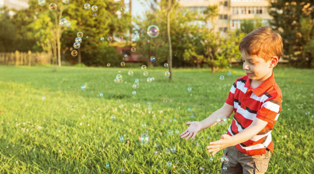istock Happy boy playing with soap bubbles in the park 1167710566