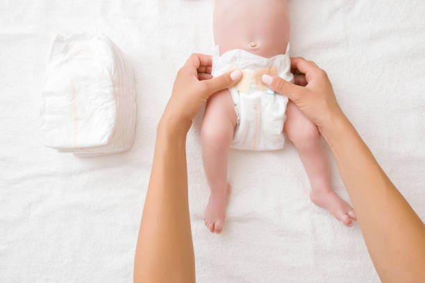 les mains de mère changeant la couche pour le bébé sur la serviette blanche. closeup. point de vue tiré. vue du haut. - body women naked beauty photos et images de collection