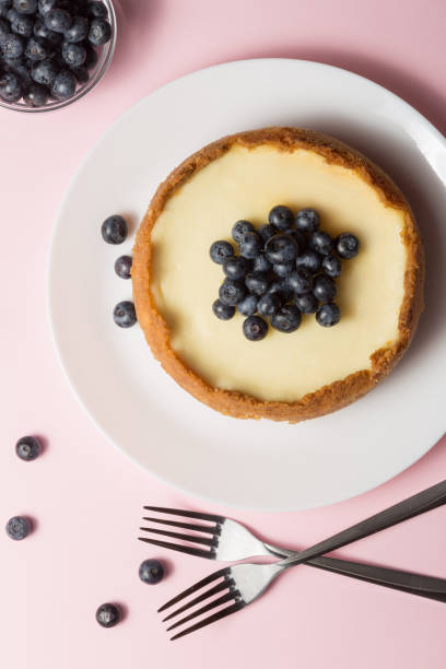 istock Plate with delicious cheesecake and two forks on pink background. 1167712018