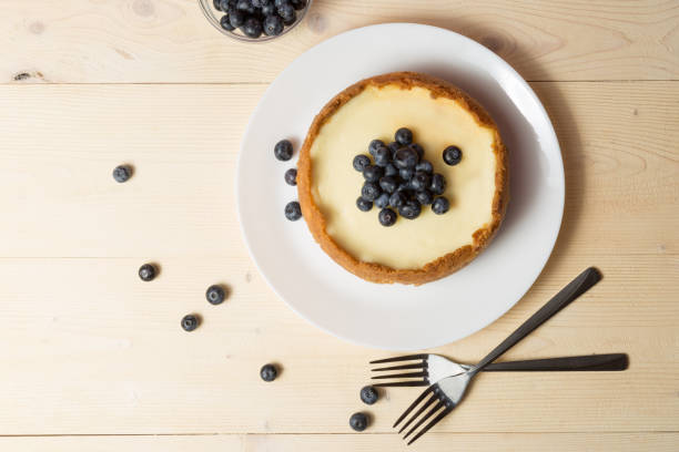 istock Plate with delicious cheesecake and two forks on wooden table. 1167712020