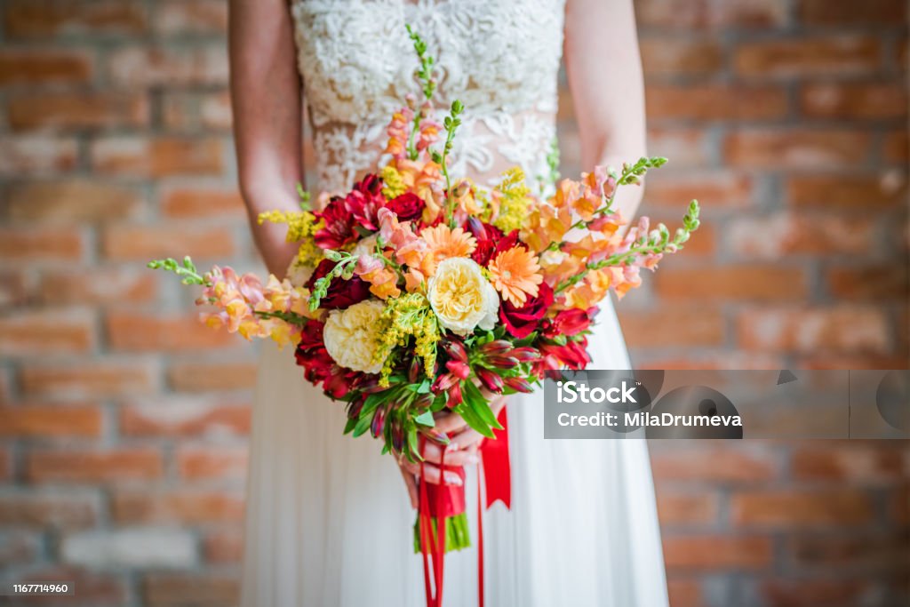 Bride holding a beautiful boho bouquet made of red and yellow fresh flowers Adult Stock Photo