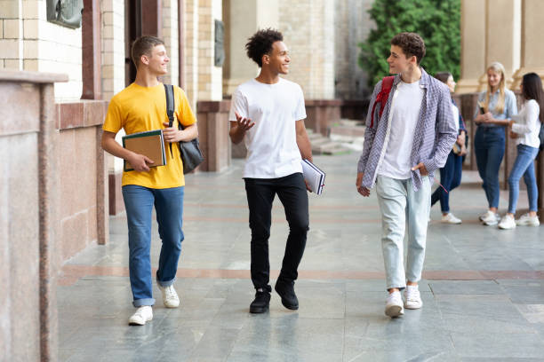 estudiantes universitarios caminando en el campus y charlando al aire libre - three boys fotografías e imágenes de stock