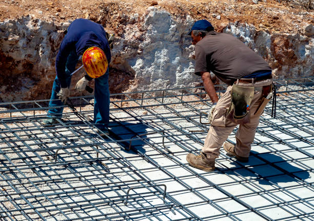 bauarbeiter in hardhat und einheitlicher montage von bindedrähten an bewehrungsstahlstäben auf der baustelle - formworks stock-fotos und bilder