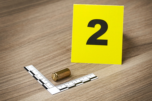 Crime Scene Investigation - bullet casing as a piece of evidence placed with forensic ruler and yellow marker for documentation