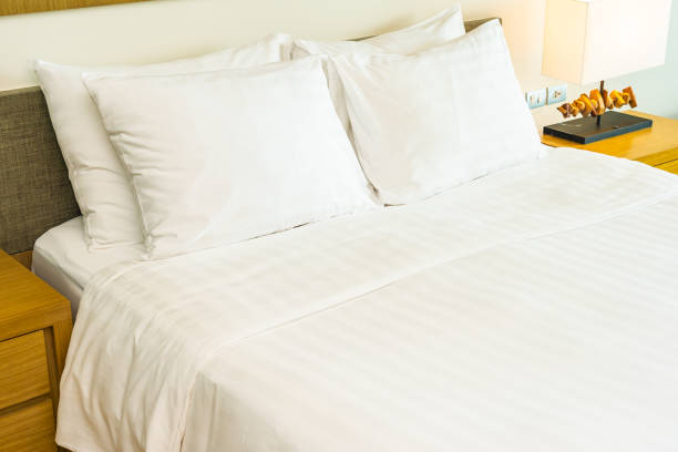 istock White comfortable pillow on bed decoration with light lamp 1167721179