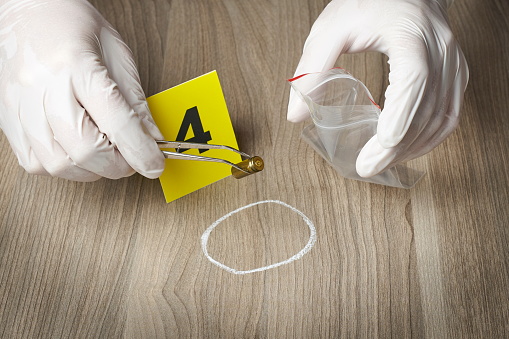 forensic officer collecting a bullet casing as a piece of evidence