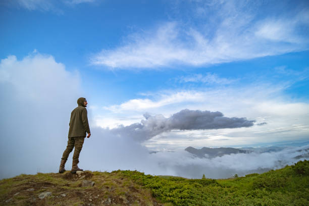 istock The man standing on the mountain on the white clouds background 1167722790