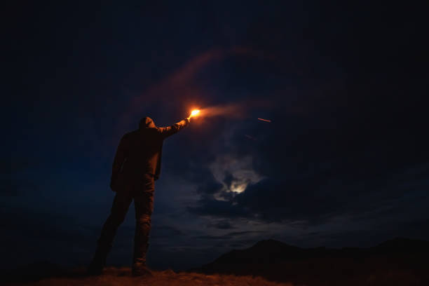 Photo of The man with a firework stick standing on the night mountain