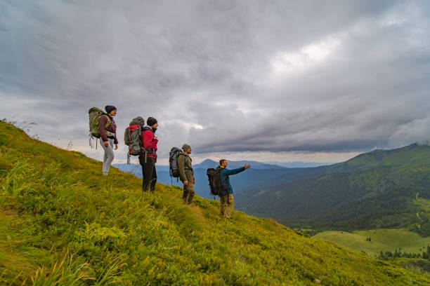 istock The four active people with backpacks standing on the green mountain 1167722877
