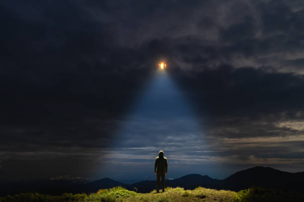 The UFO shines on a male standing on the mountain stock photo