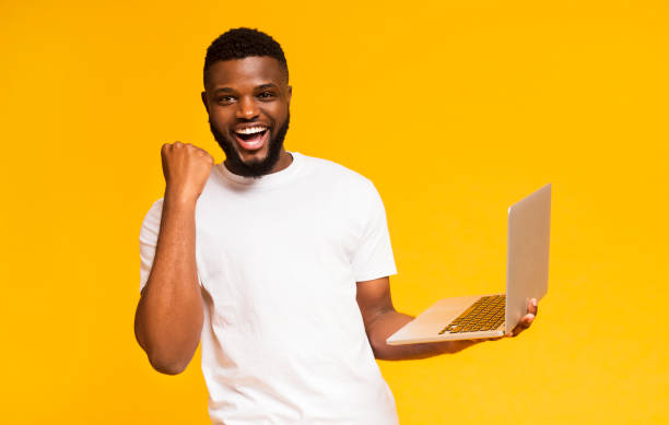 istock Excited african man celebrating win with laptop 1167723759