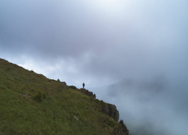 istock The man standing on the rock in clouds 1167724143