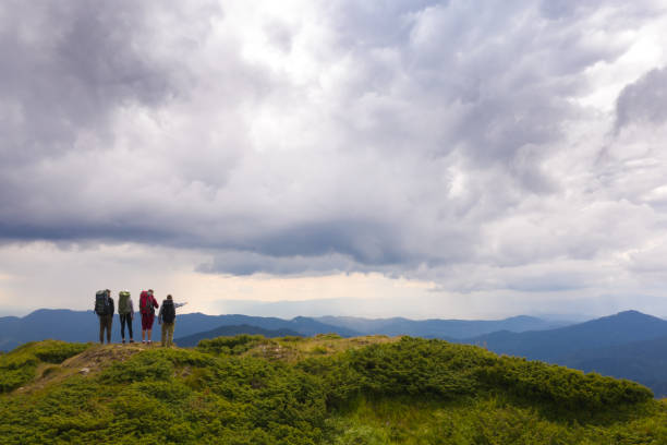 istock The four people with backpacks standing on a mountain against beautiful clouds 1167724367