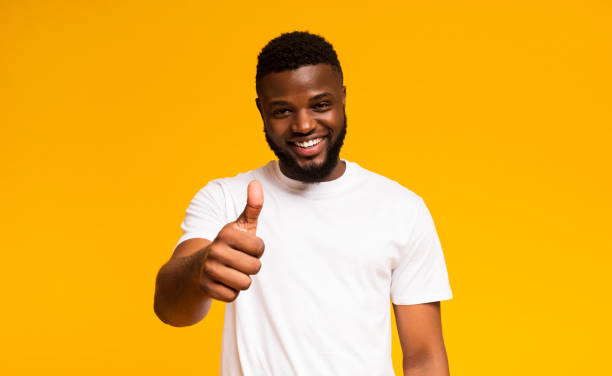 istock Happy guy showing thumb up and smiling over yellow background 1167724550
