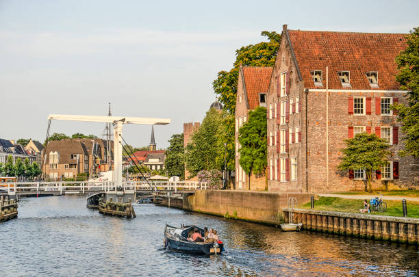 Zwolle; The Netherlands; July 24; 2019: little boat cruising in Thorbecke canal, approaching a drawbridge and historic houses, on a summer evening