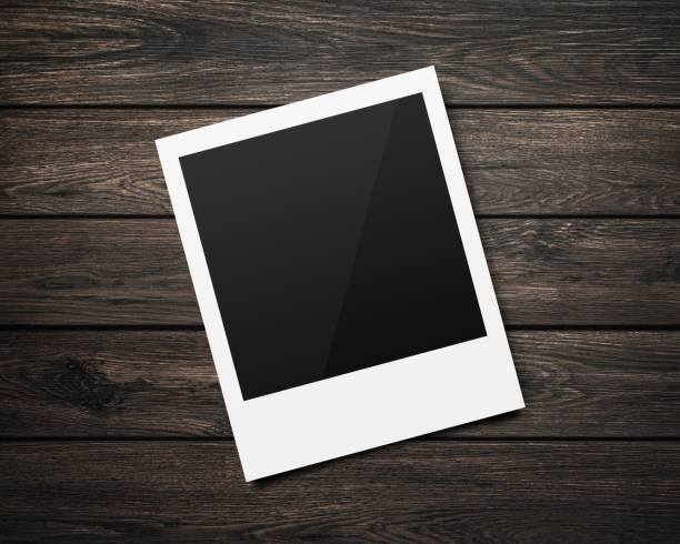 istock Empty polaroid photo frames mockups template on a wooden table background for putting your pictures. Paper sheet for printing images or recording picture of film cameras. 1167725760