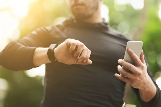 mann überprüft daten auf fitness-tracker nach dem training im freien - fährtensucher stock-fotos und bilder